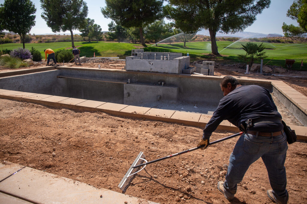 A worker smoothes out soil during landscape construction